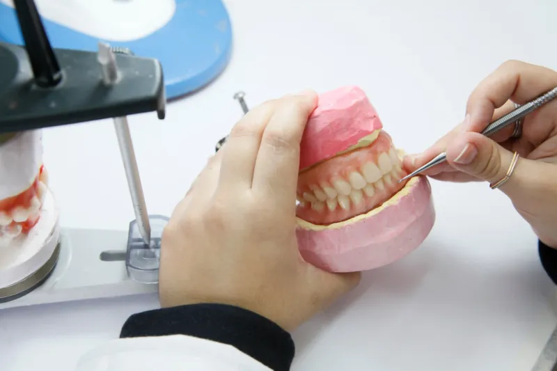 Adobestock 455823273 Copy Dental professional examining a denture